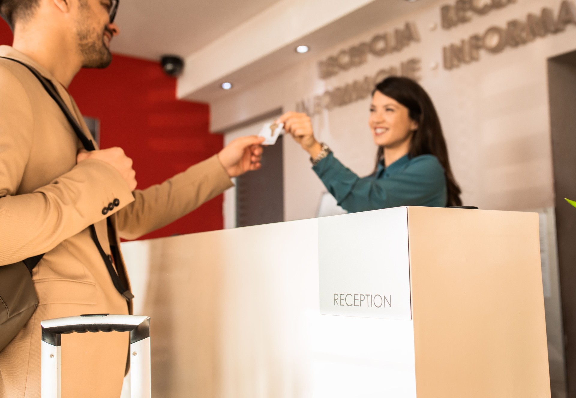 La réceptionniste souriante derrière le comptoir de l’hôtel donne au client la clé de la chambre.